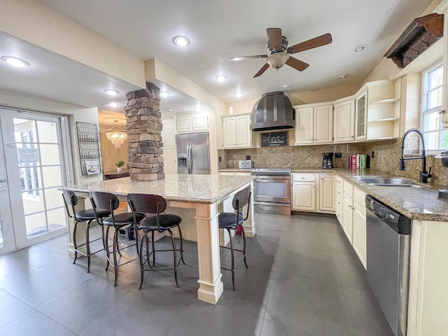 kitchen featuring stainless steel appliances, sink, decorative columns, a breakfast bar, and a spacious island