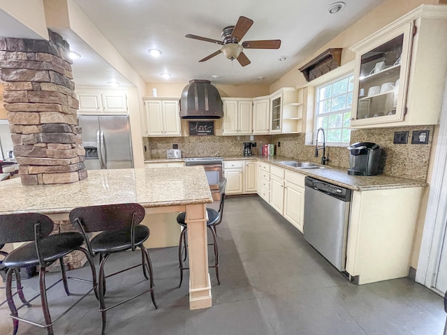 kitchen with ventilation hood, appliances with stainless steel finishes, light stone countertops, decorative backsplash, and sink