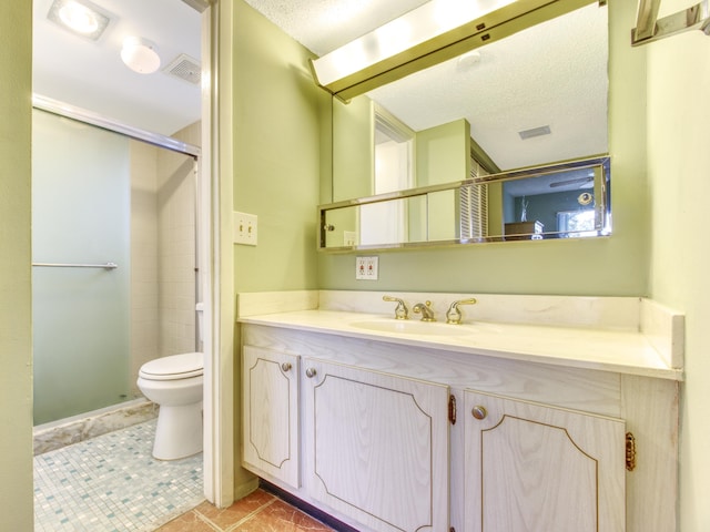 bathroom featuring tile patterned floors, toilet, a textured ceiling, vanity, and a shower with door