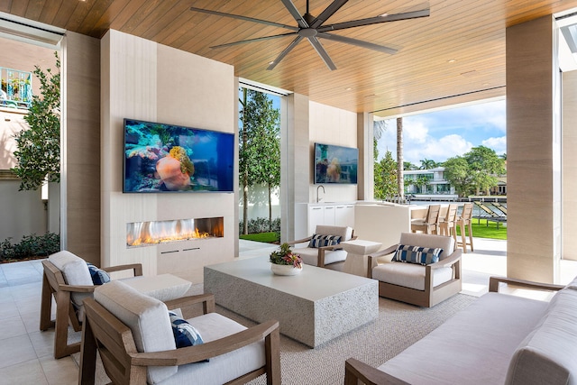 view of patio with ceiling fan, a wet bar, and an outdoor living space with a fireplace