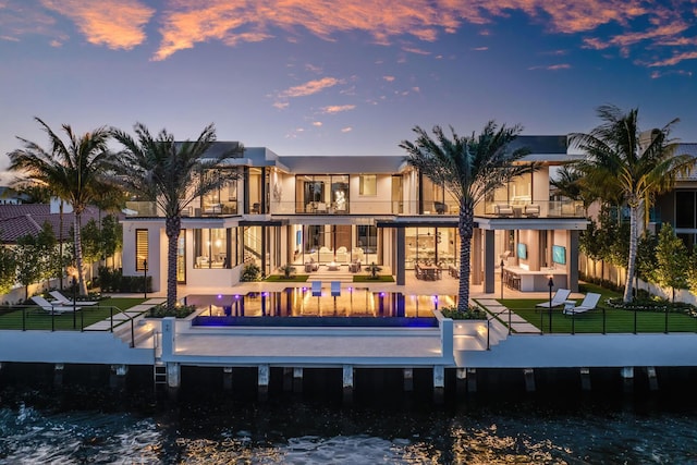 1520 Royal Palm Way, Boca Raton, FL 33432 - back of property at dusk featuring a patio area, a swimming pool, and stucco siding