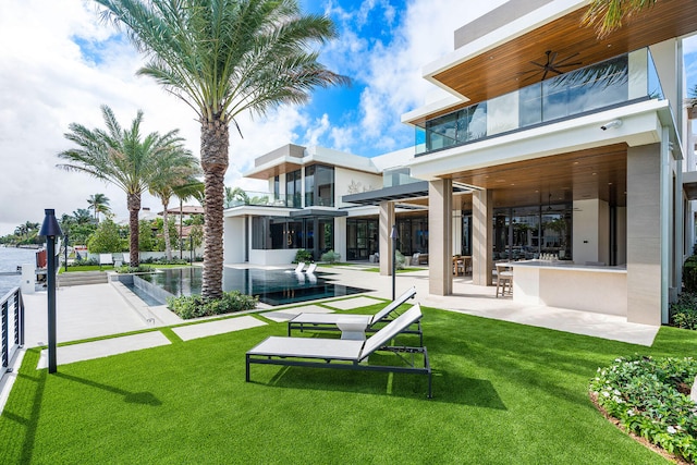 back of house featuring an outdoor bar, a yard, ceiling fan, and a pool