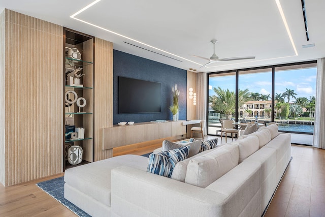 living room with hardwood / wood-style floors, a wall of windows, and ceiling fan