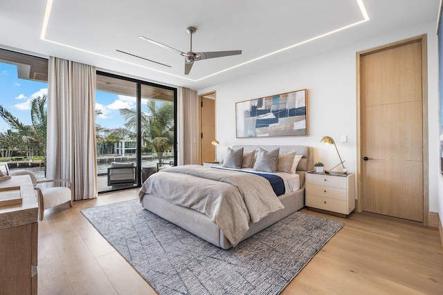 1520 Royal Palm Way, Boca Raton, FL 33432 - bedroom featuring expansive windows, access to outside, light wood-style flooring, a tray ceiling, and a ceiling fan