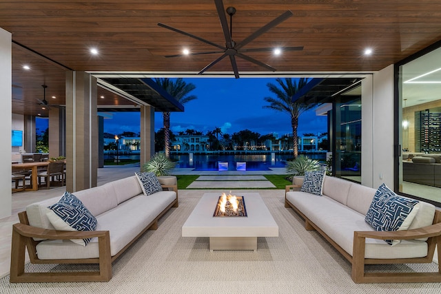 patio terrace at dusk featuring a water view and an outdoor living space with a fire pit