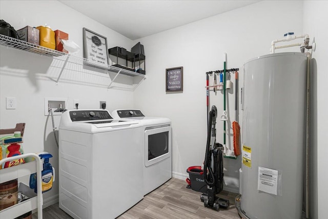 clothes washing area with water heater, light hardwood / wood-style flooring, and washer and clothes dryer