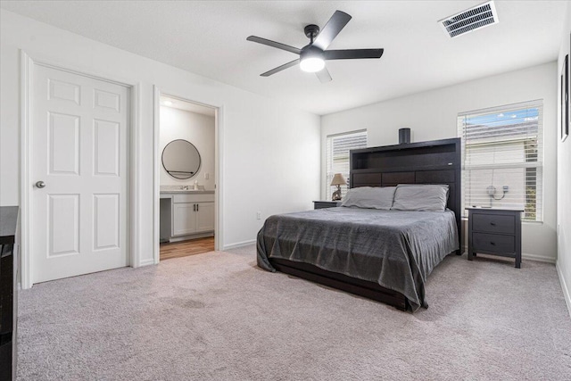 bedroom featuring ensuite bath, light carpet, ceiling fan, and sink