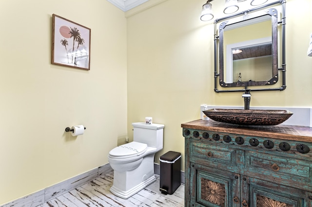 bathroom with vanity, toilet, and ornamental molding