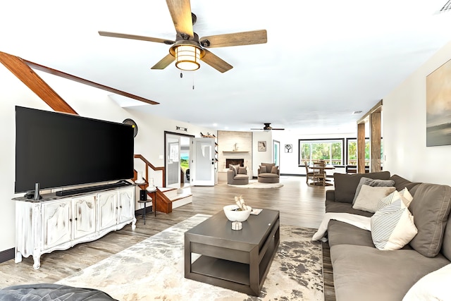 living room featuring ceiling fan, hardwood / wood-style floors, and a large fireplace