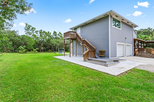 rear view of property featuring a garage, a wooden deck, a yard, and a patio area