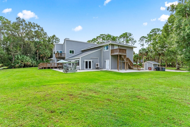 rear view of property featuring a patio, a lawn, an outdoor structure, and a wooden deck