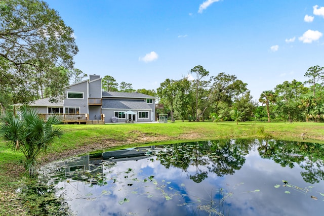 rear view of property featuring a yard and a deck with water view