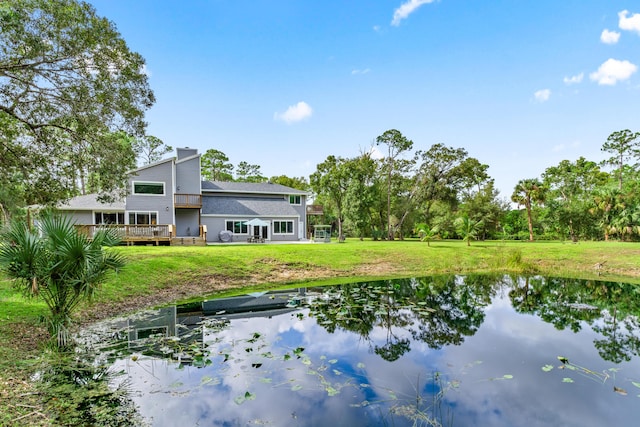 12151 Old Indiantown Rd, Jupiter, FL 33478 - rear view of house with a deck with water view, a chimney, and a lawn