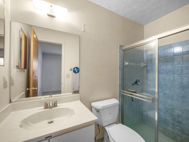 bathroom featuring vanity, a shower with shower door, a textured ceiling, and toilet