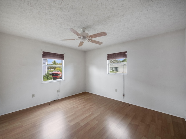 spare room featuring a textured ceiling, wood-type flooring, a healthy amount of sunlight, and ceiling fan