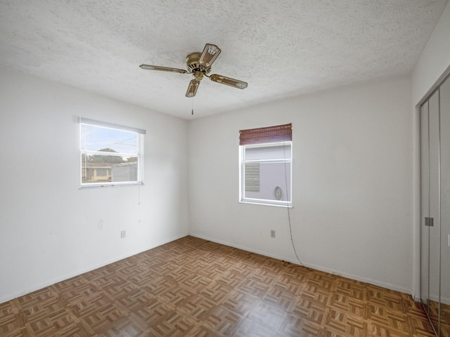 spare room with light parquet flooring, a textured ceiling, and ceiling fan