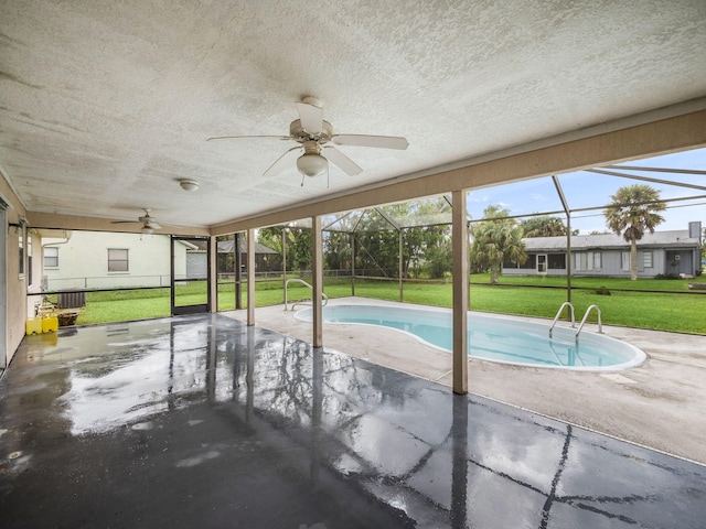 view of swimming pool with ceiling fan, a lawn, glass enclosure, and a patio area