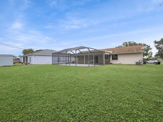 rear view of house featuring central AC unit, a yard, and glass enclosure