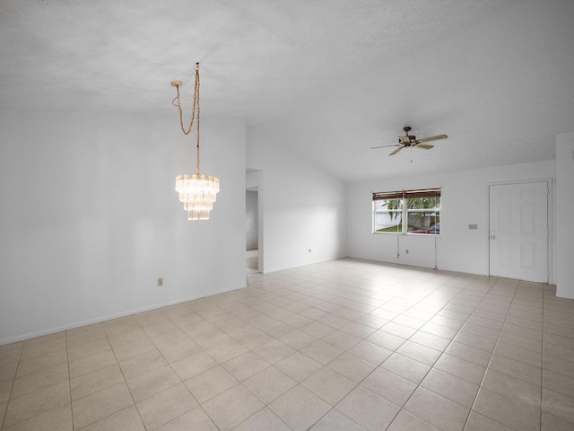 spare room featuring ceiling fan with notable chandelier, light tile patterned floors, and lofted ceiling