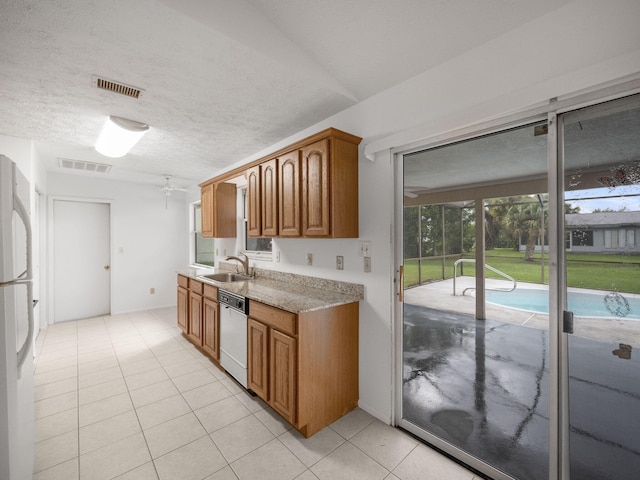 kitchen featuring sink, ceiling fan, a textured ceiling, light tile patterned floors, and white appliances