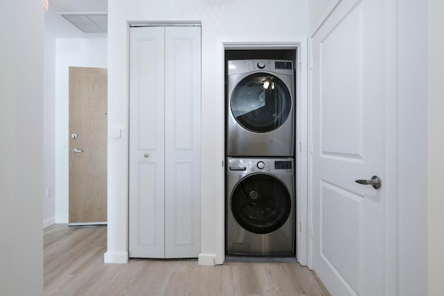 laundry room with stacked washer / dryer and light hardwood / wood-style floors