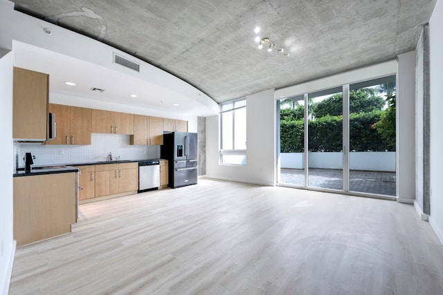 kitchen featuring stainless steel appliances, light hardwood / wood-style floors, sink, tasteful backsplash, and light brown cabinets