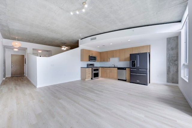 kitchen with appliances with stainless steel finishes, sink, ceiling fan, and light hardwood / wood-style flooring