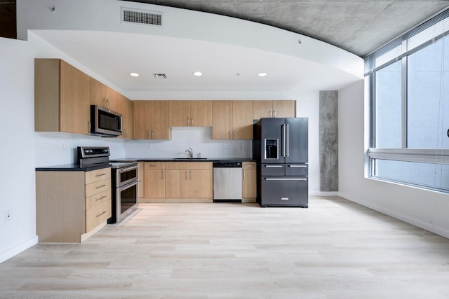 kitchen with light wood-type flooring, stainless steel appliances, sink, and a wealth of natural light