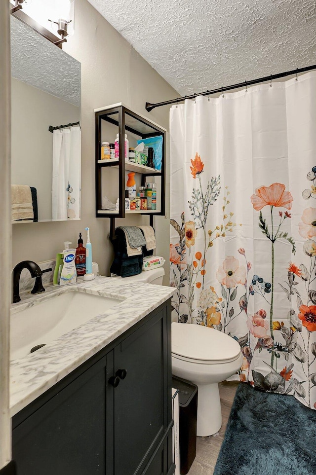 bathroom with toilet, vanity, a textured ceiling, and wood-type flooring