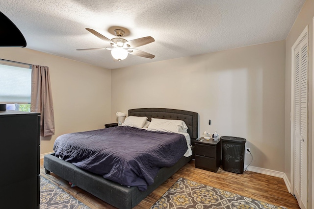 bedroom featuring a textured ceiling, hardwood / wood-style floors, ceiling fan, and a closet