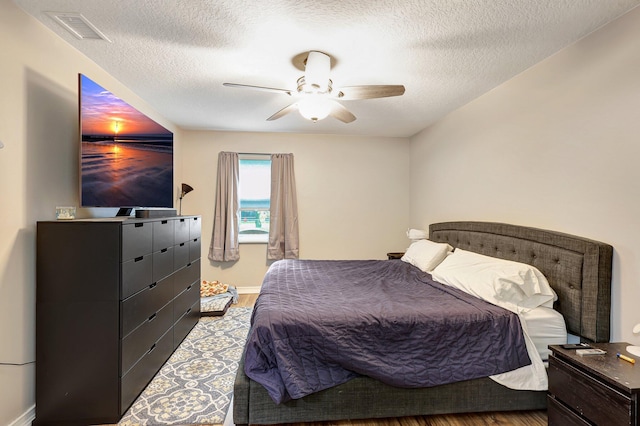 bedroom featuring light hardwood / wood-style floors, a textured ceiling, and ceiling fan