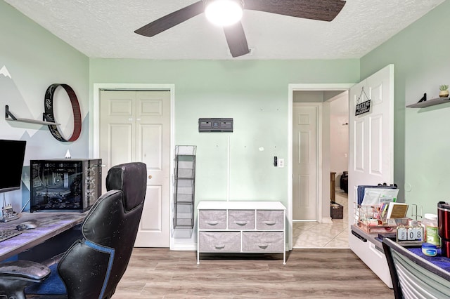 office area featuring light hardwood / wood-style floors, ceiling fan, and a textured ceiling