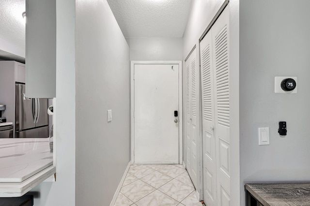 entryway with a textured ceiling and light tile patterned floors