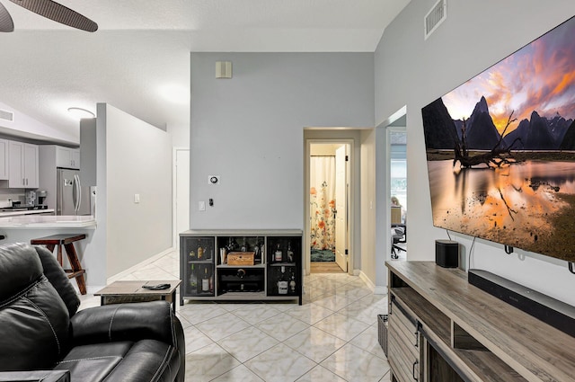 living room featuring lofted ceiling, a textured ceiling, light tile patterned floors, and ceiling fan