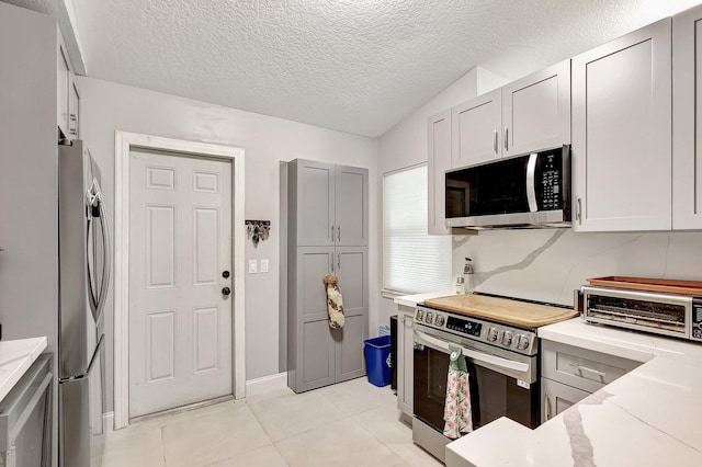 kitchen with stainless steel appliances, lofted ceiling, a textured ceiling, and light stone counters