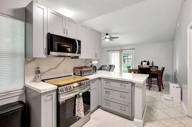 kitchen with tasteful backsplash, light tile patterned flooring, stainless steel appliances, kitchen peninsula, and ceiling fan