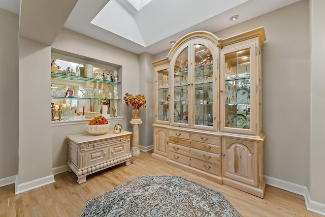 interior space featuring a skylight and light hardwood / wood-style floors