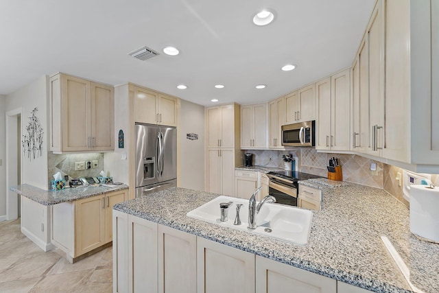 kitchen featuring appliances with stainless steel finishes, backsplash, light stone counters, and sink