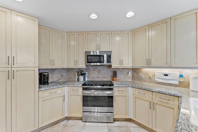 kitchen with cream cabinetry, appliances with stainless steel finishes, and backsplash