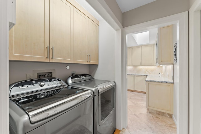 clothes washing area with washing machine and clothes dryer, light tile patterned flooring, and cabinets