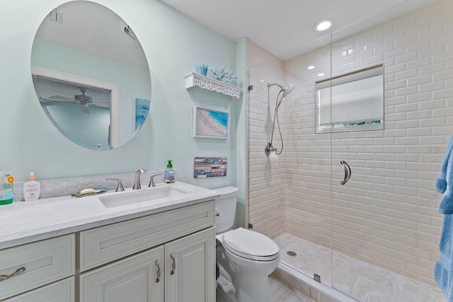 bathroom with vanity, toilet, a shower with shower door, and ceiling fan