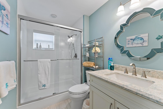 bathroom featuring vanity, toilet, and a shower with shower door