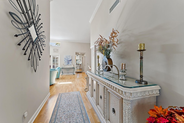 hallway featuring crown molding and light hardwood / wood-style floors