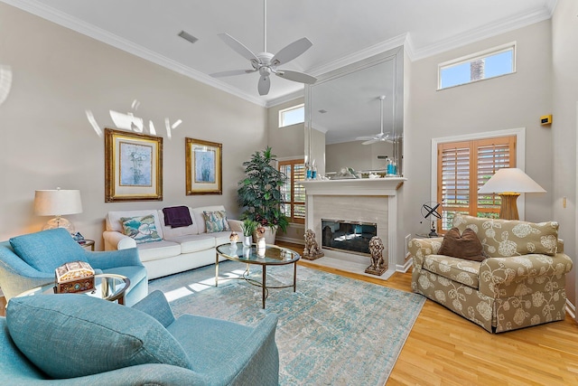 living room with a high ceiling, hardwood / wood-style floors, ornamental molding, and ceiling fan