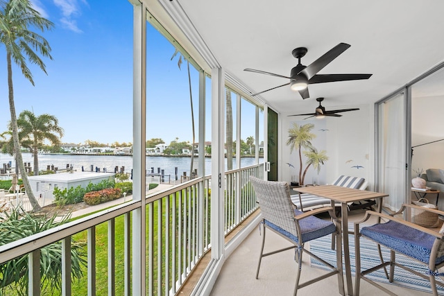 sunroom featuring a water view and ceiling fan