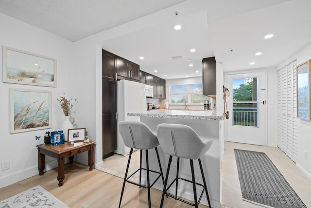 kitchen featuring white appliances, dark brown cabinets, sink, and light hardwood / wood-style flooring