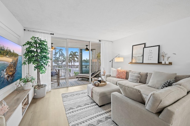 living room featuring light hardwood / wood-style floors, a textured ceiling, and ceiling fan