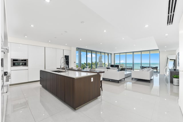 kitchen with dark brown cabinetry, white cabinets, sink, and floor to ceiling windows