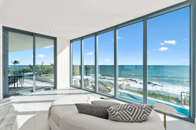 bedroom with a view of the beach, a water view, and floor to ceiling windows