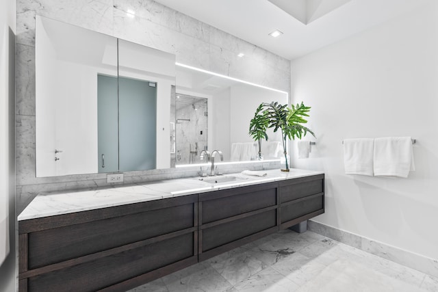 bathroom featuring a shower with door and vanity